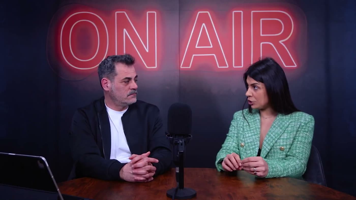 La registrazione in studio, due persone ai microfoni sotto il neon ON AIR